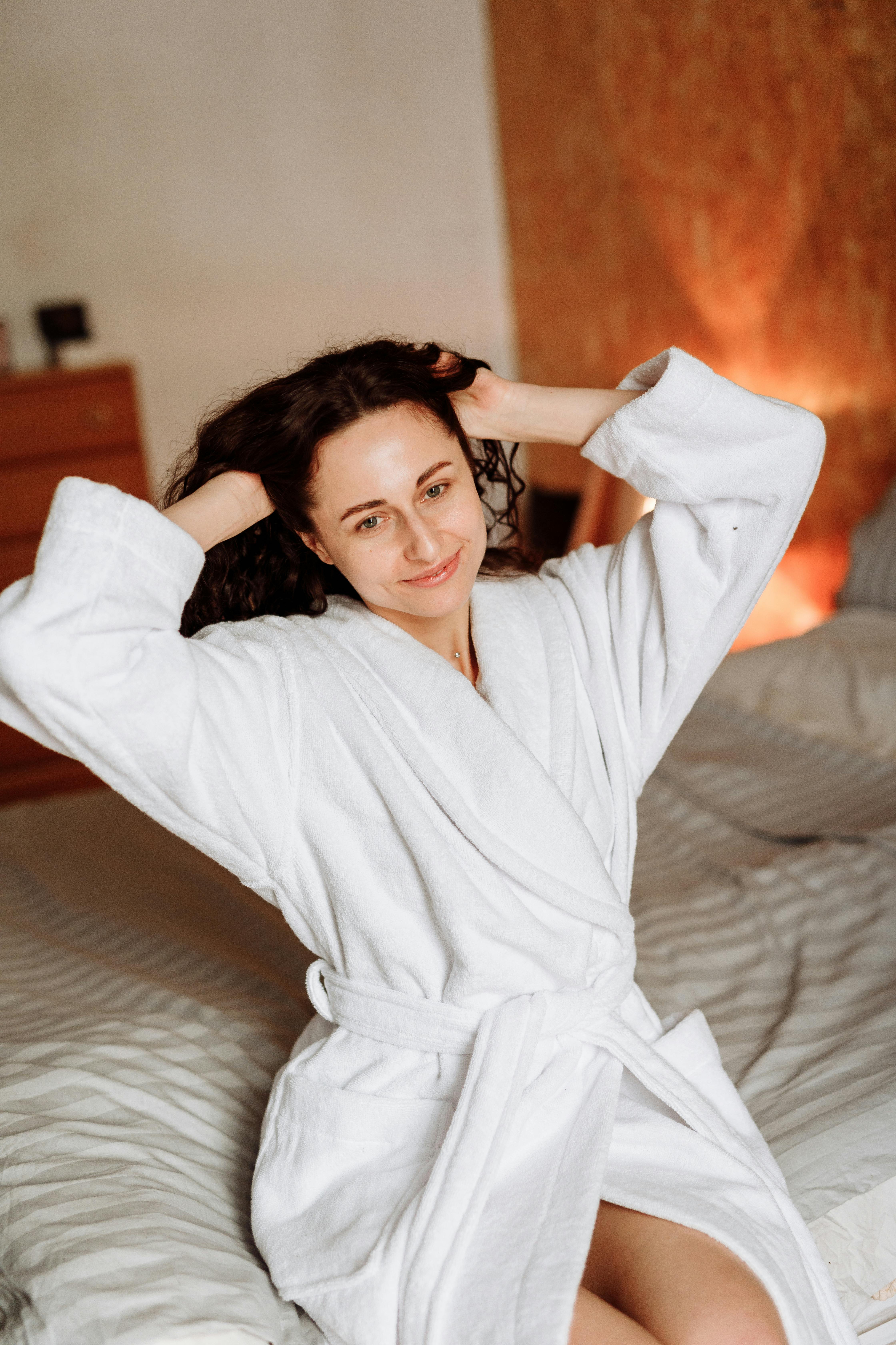 woman in white robe lying on bed