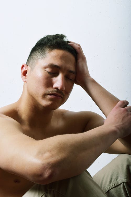 Depressed man touching head on light background