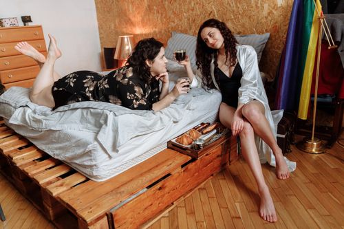Free Two women enjoying a relaxed moment indoors with wine, highlighting romantic and intimate vibes. Stock Photo