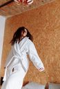 Woman in White Robe Sitting on Brown Carpet