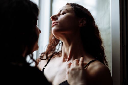Free Close-up of two women embracing, capturing an intimate and romantic moment by the window in soft lighting. Stock Photo