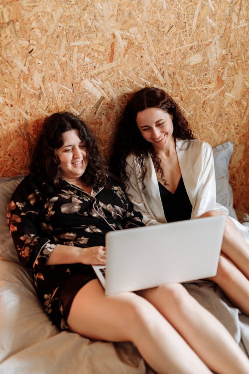 Free Women Watching on Laptop in Bed and Smiling Stock Photo