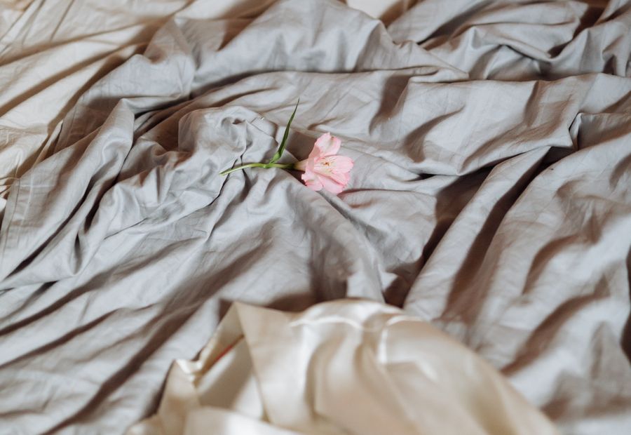 A single rose resting on soft linen bedding