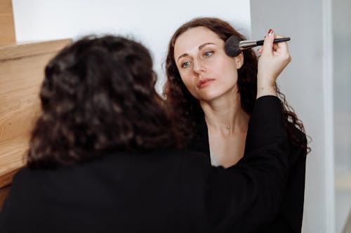 Free Woman in Black Long Sleeve Shirt Holding Makeup Brush Stock Photo