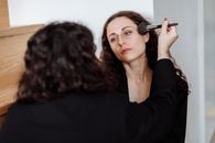 Woman in Black Long Sleeve Shirt Holding Makeup Brush