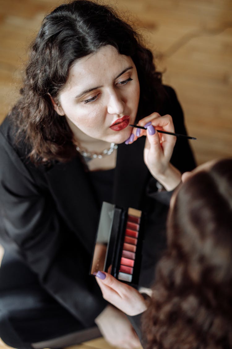 A Person Applying Makeup To A Woman