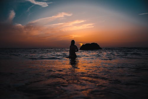 日没時の海の上の女性のシルエット