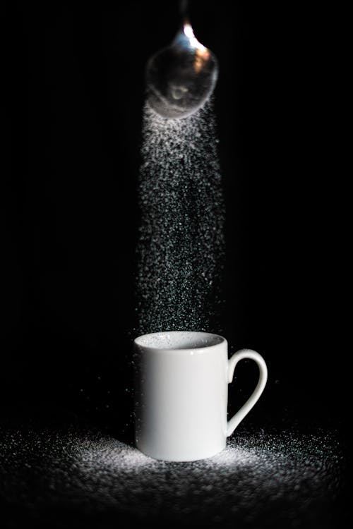 Free Studio Shot of Sugar Sliding from a Spoon into a Cup  Stock Photo