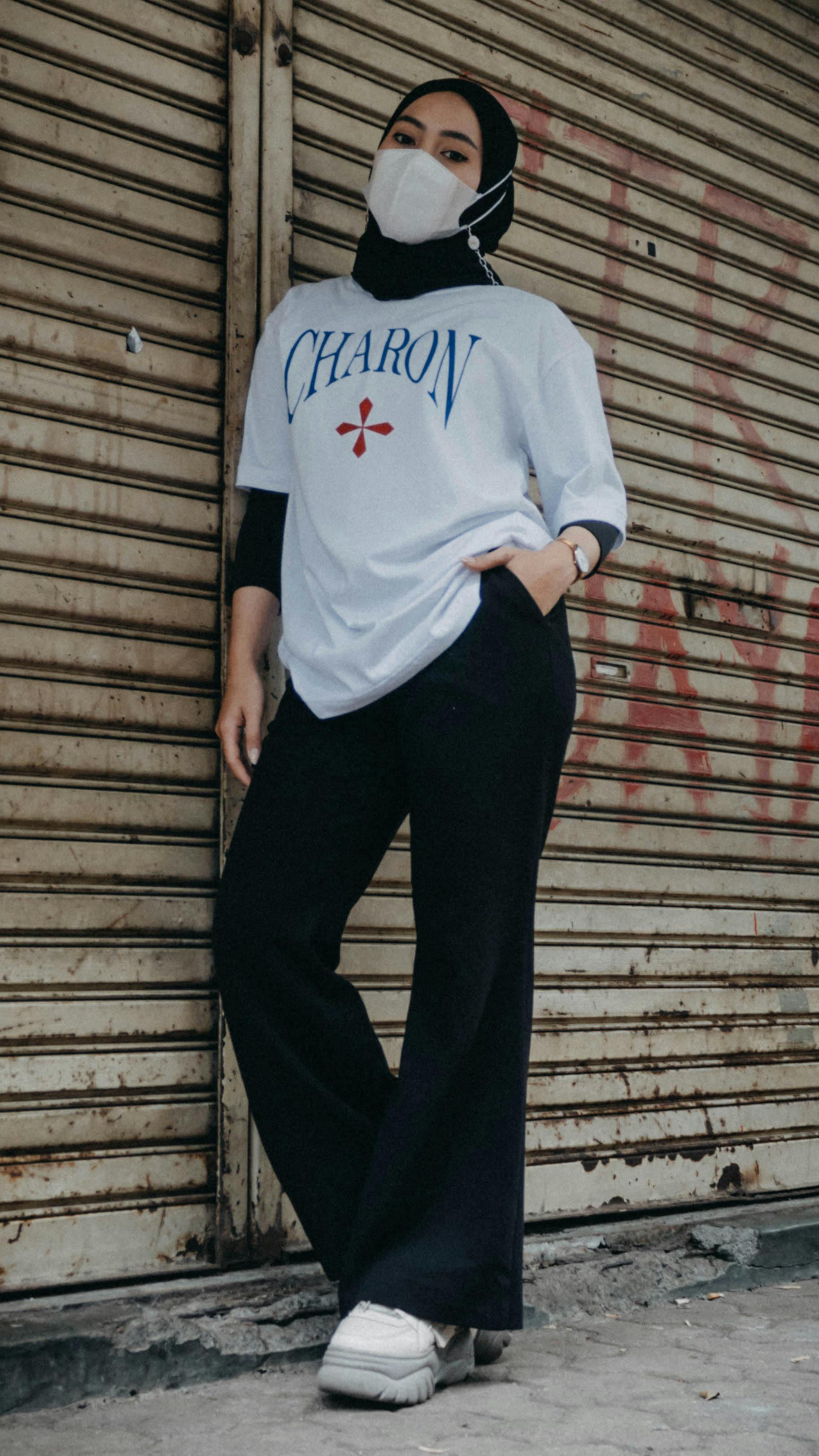 Stylish woman in a hijab stands confidently on an urban street, showcasing modern fashion.