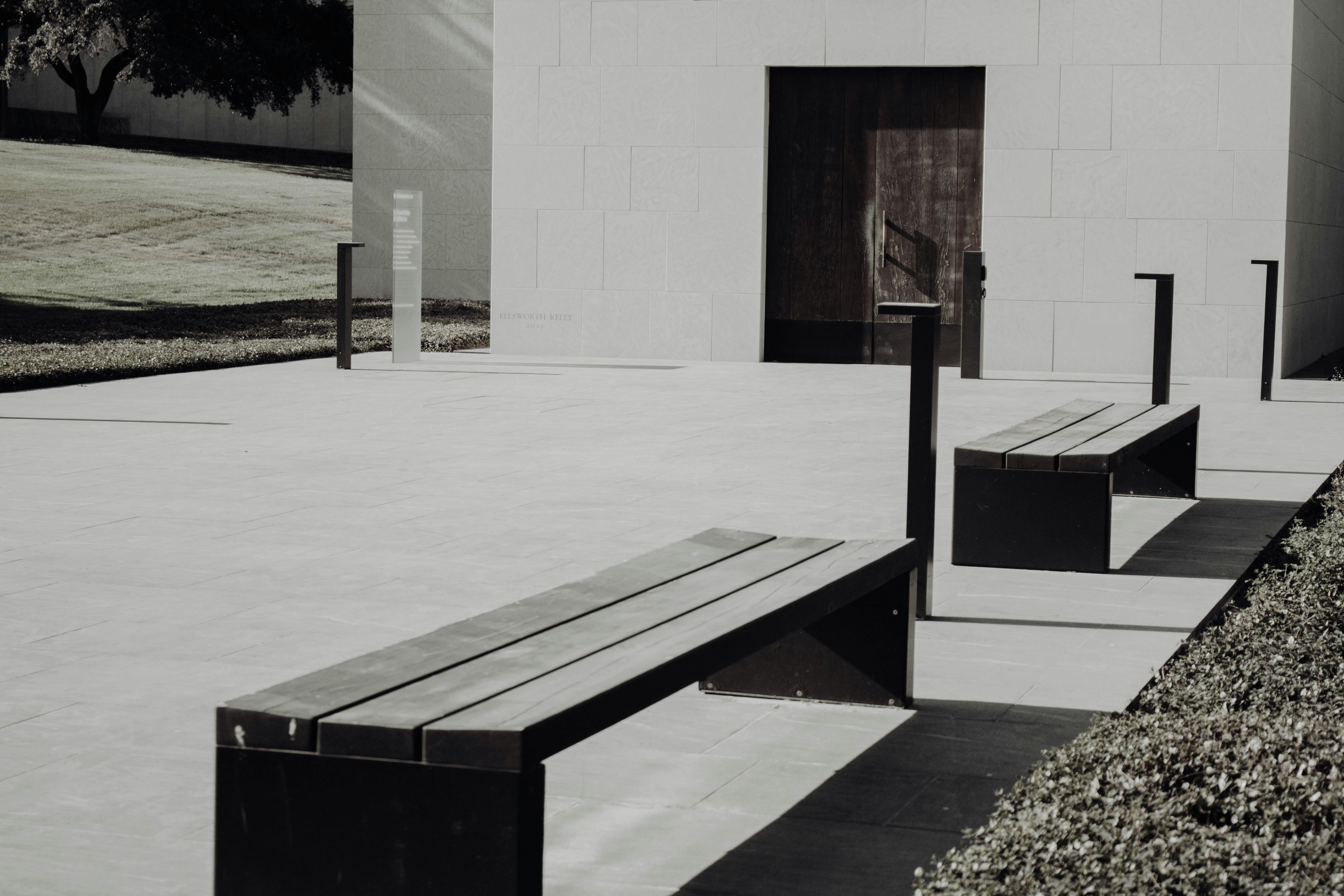 brown wooden bench near white concrete wall