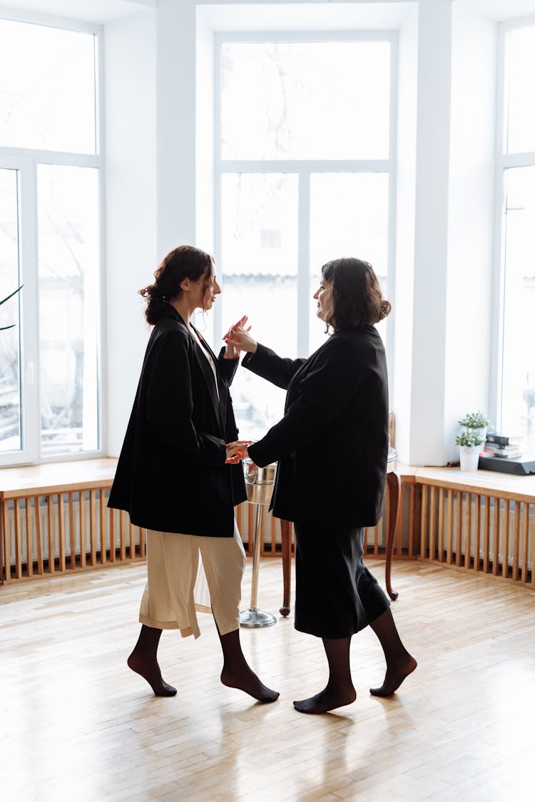 A Same Sex Couple In Black Blazers Holding Hands