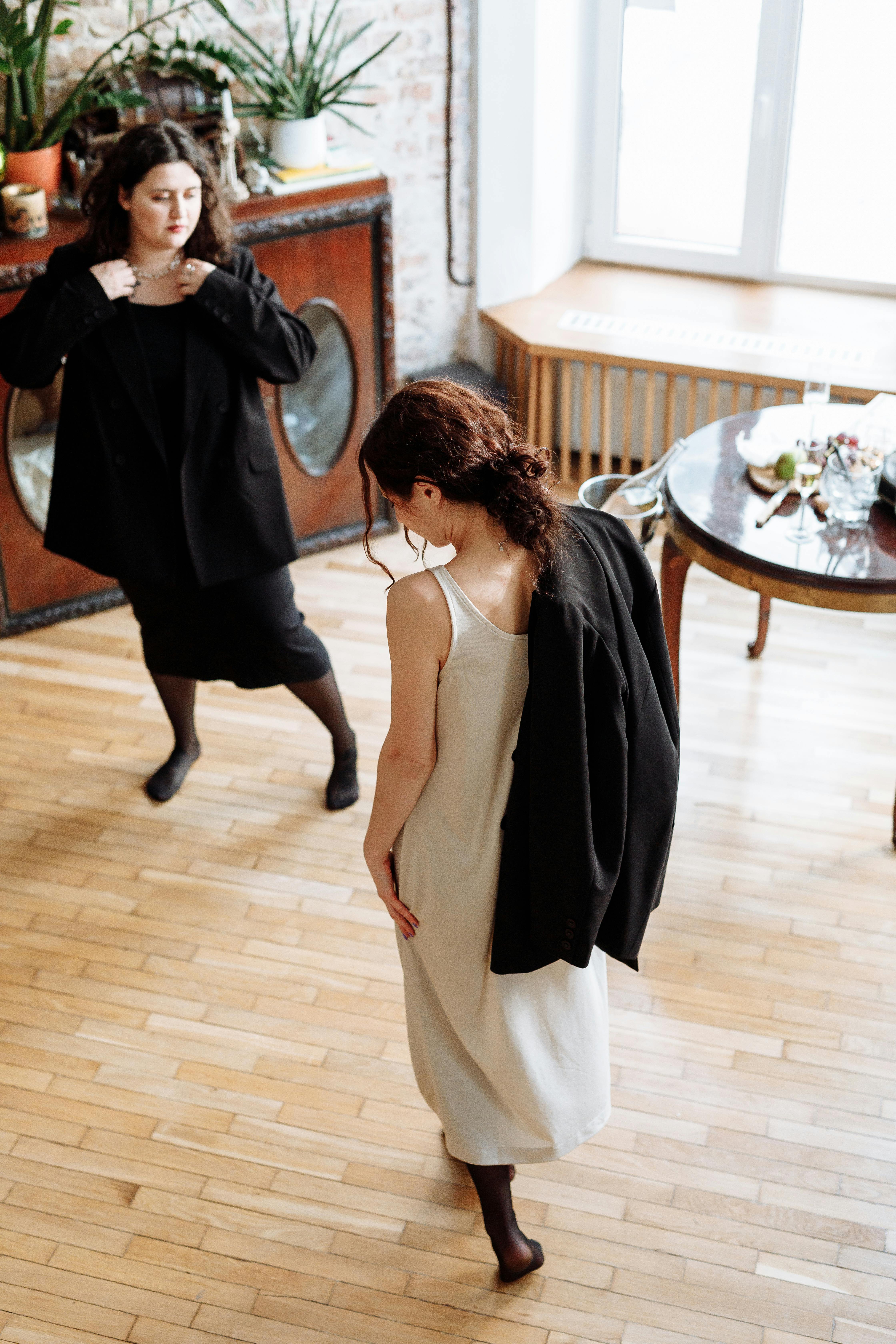 woman in black spaghetti strap top and white pants standing beside woman in white pants