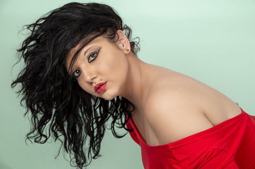 Free Striking studio portrait of a woman in a red top with captivating makeup and hairstyle. Stock Photo
