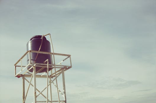 An industrial water tank atop a metal frame against a clear sky, showcasing infrastructure design.