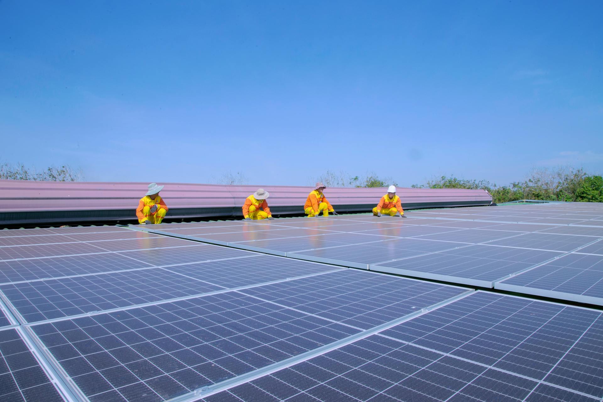 Team of solar technicians installing panels under a clear sky, focusing on renewable energy.