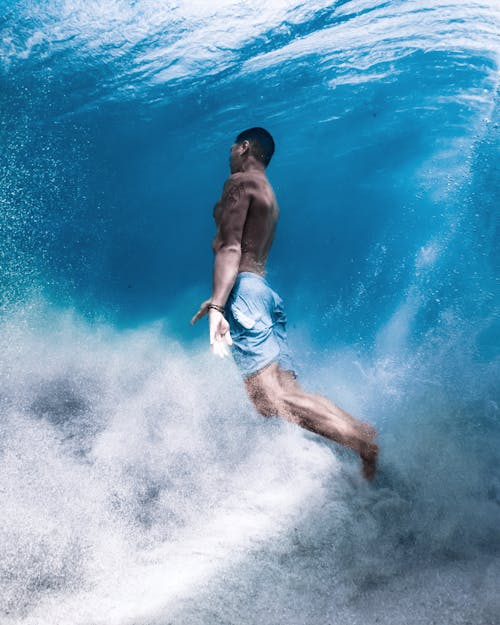 Unrecognizable male surfer in azure sea wave