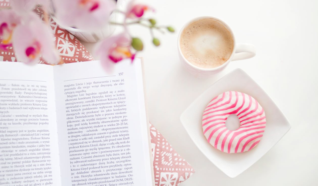 A book, cup of coffee and flavoured donut on Square White Ceramic Bowl