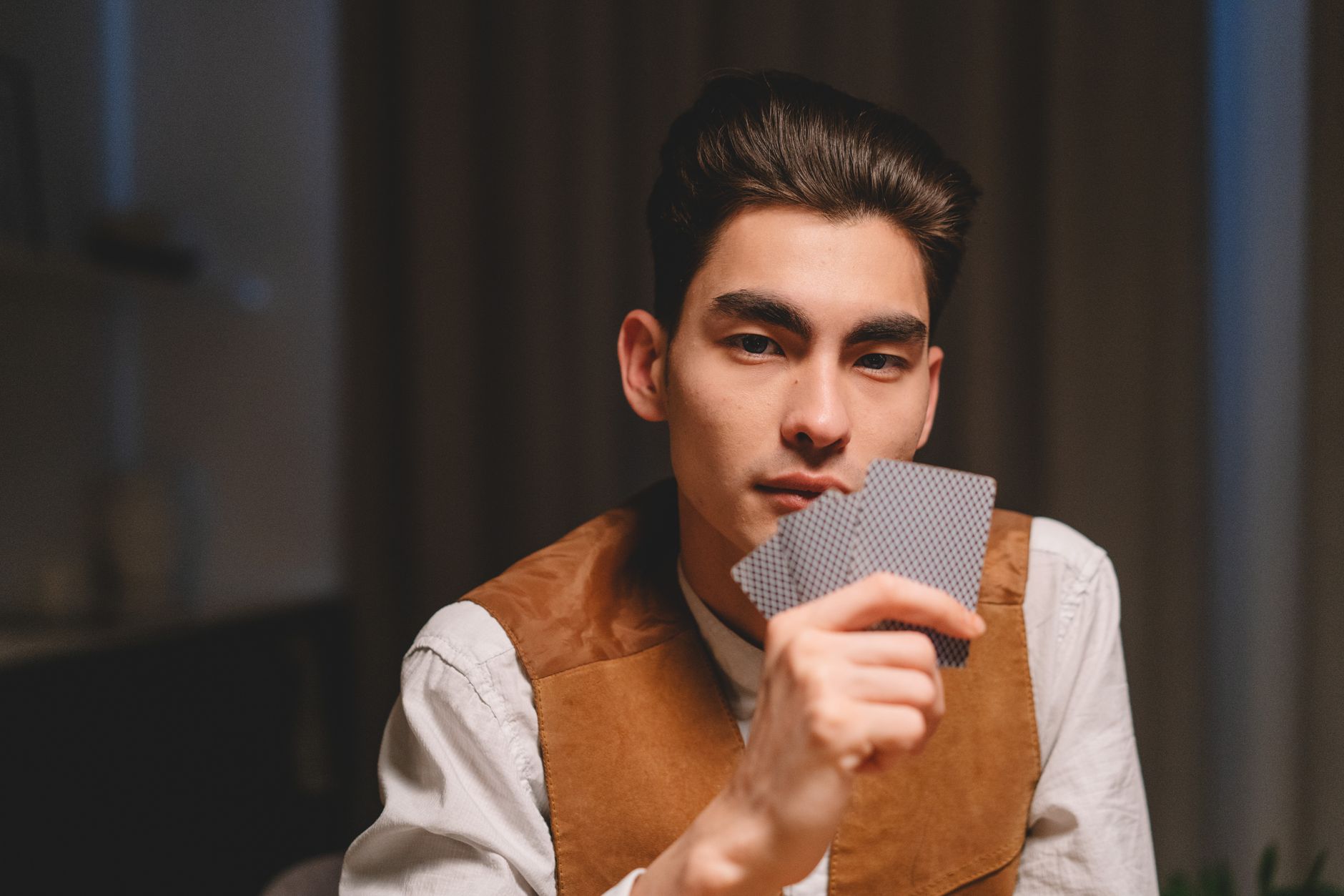 A focused Indian card player studying three cards at a green felt table, chips neatly arranged