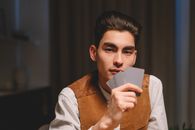 A Man Holding Playing Cards while Seriously Looking at the Camera