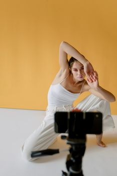 Creative portrait of a woman with a stylish pose in a minimalistic studio setting.