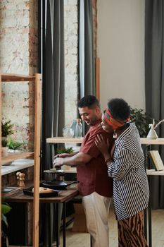 Smiling couple enjoys cooking together in a cozy indoor kitchen.