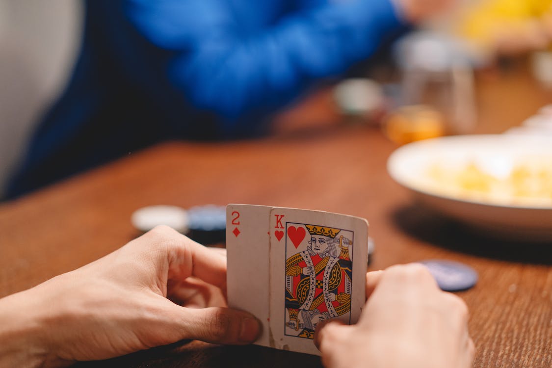 Free Selective Focus Photo of a Person's Hands Holding Playing Cards Stock Photo