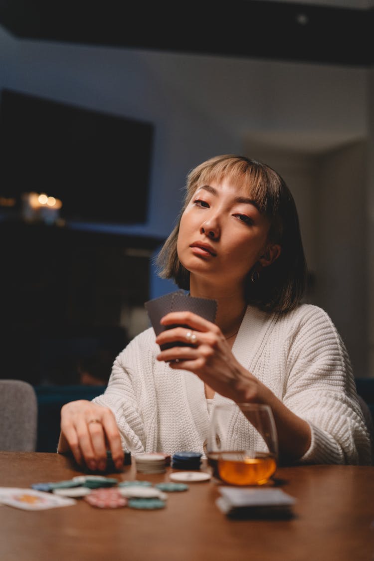 Photo Of A Woman In A White Knitted Sweater Holding Playing Cards