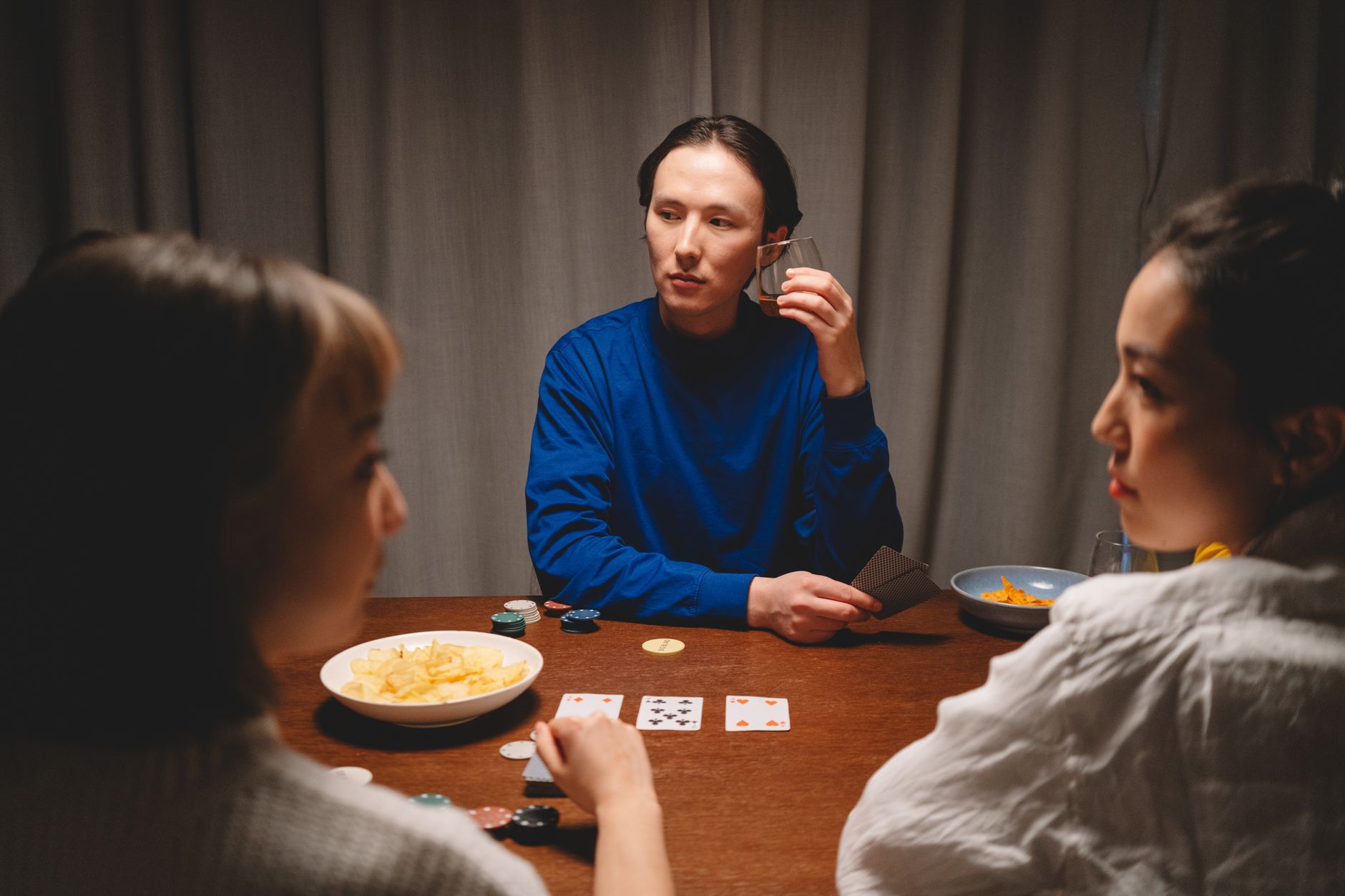 Three-card Teen Patti table on a smartphone beside neatly stacked chips under warm evening light