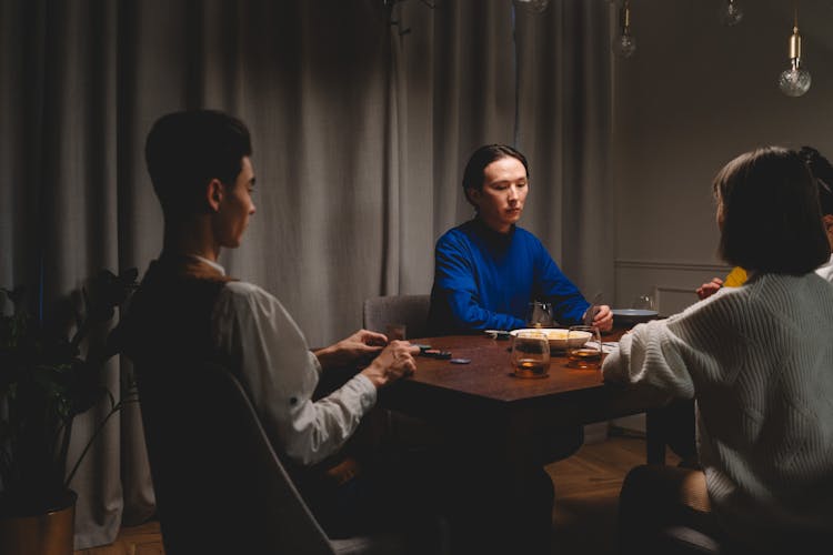 People Playing Poker On A Wooden Table