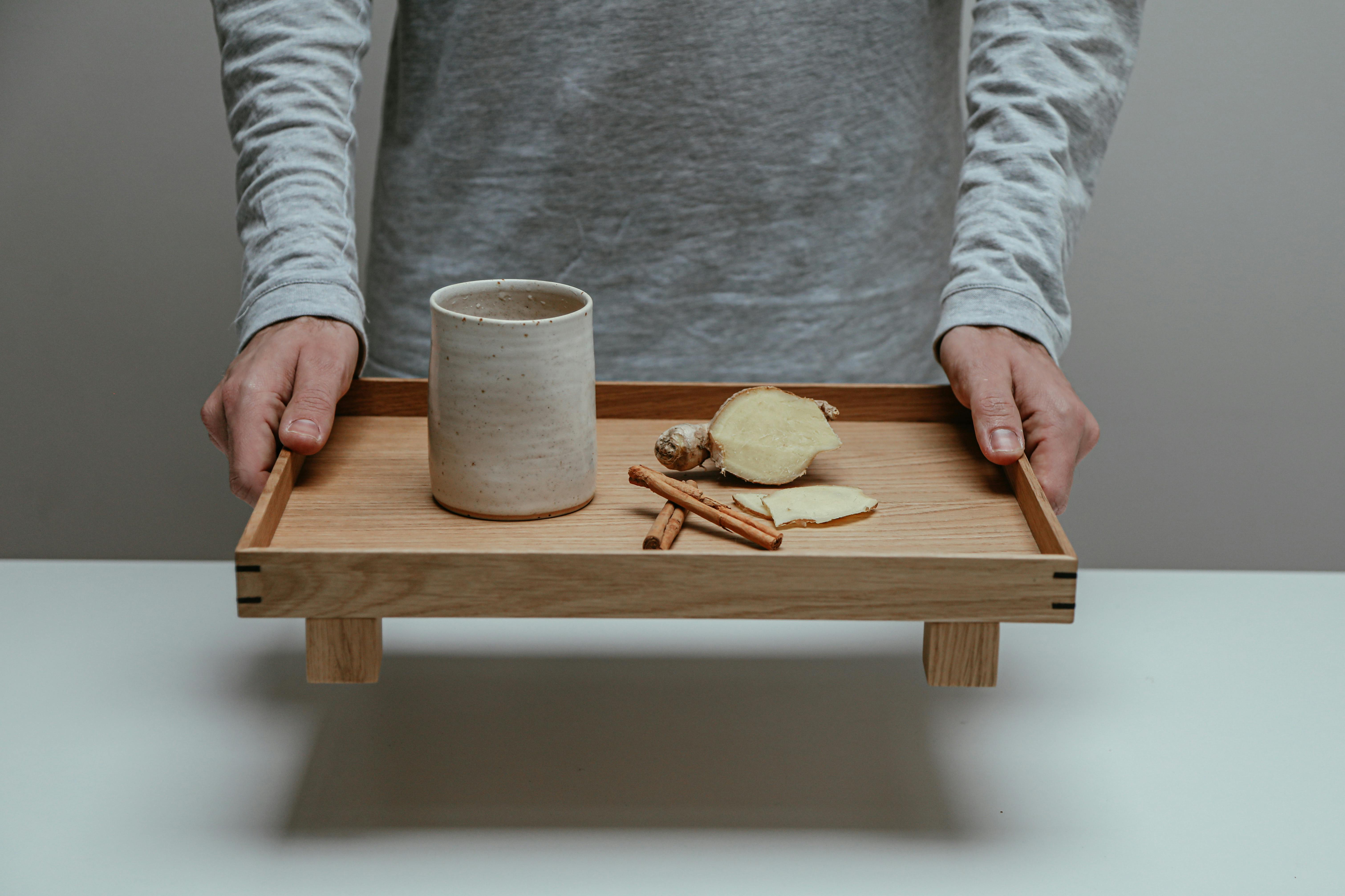 Person Holding a Wooden Serving Tray with a Cup and Herbs · Free Stock
