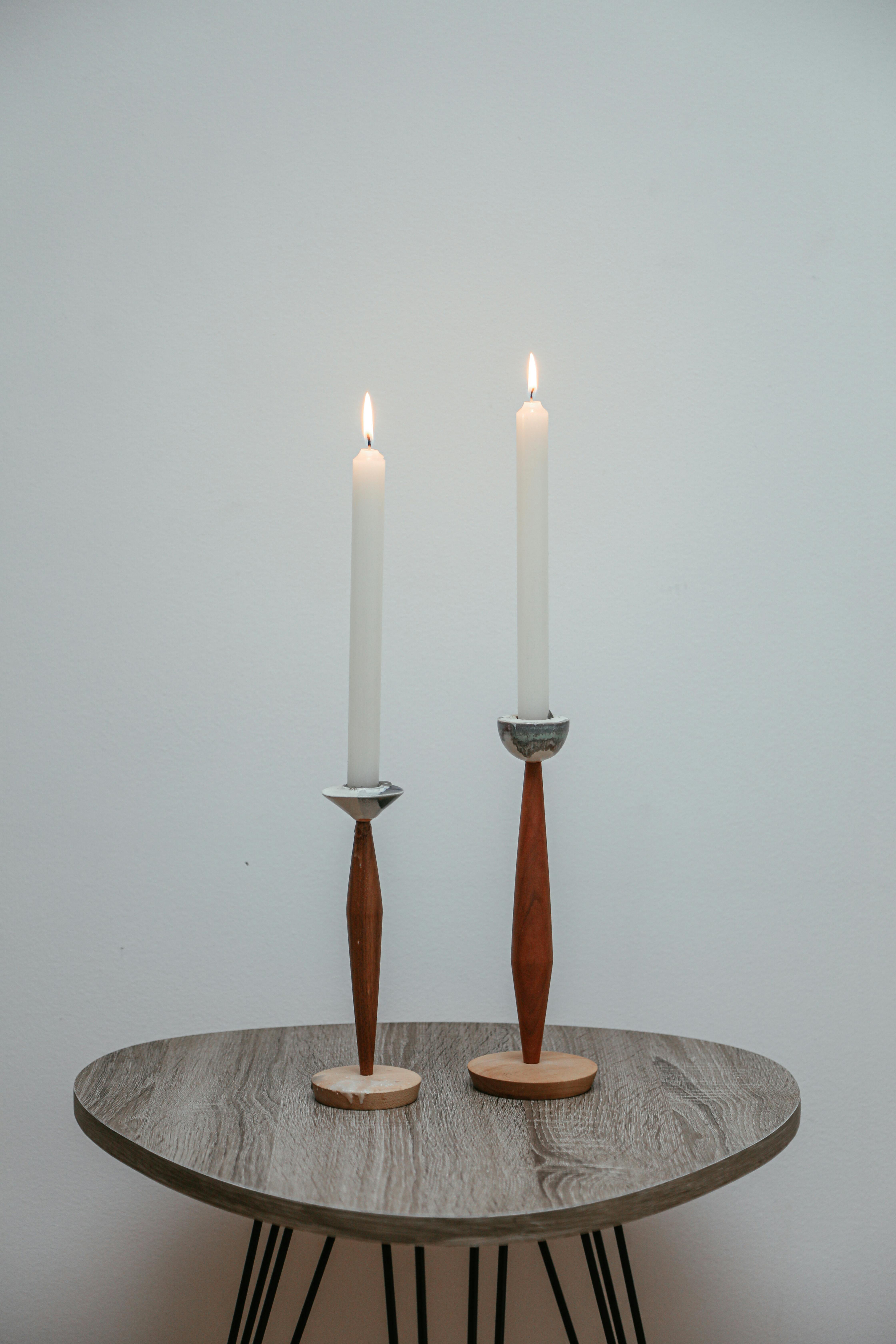 A minimalist scene with two elegant candles on a wooden table, creating a serene atmosphere.