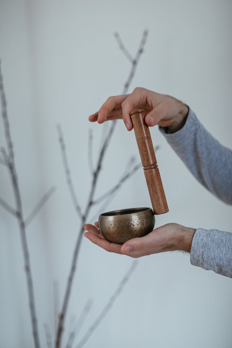 A Person Holding A Mallet And A Singing Bowl