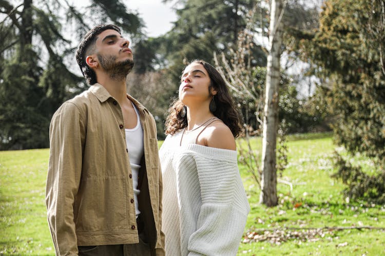 Young Man And A Girl Doing Deep Breathing In The Park