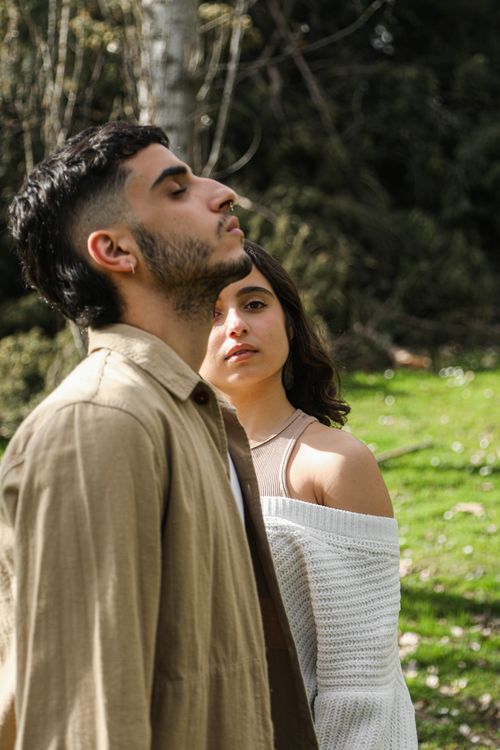 Free A young couple stands outdoors in a serene setting, enjoying a peaceful moment together. Stock Photo
