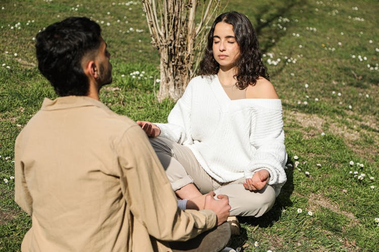 A Couple Meditating While Sitting On A Grassy Ground