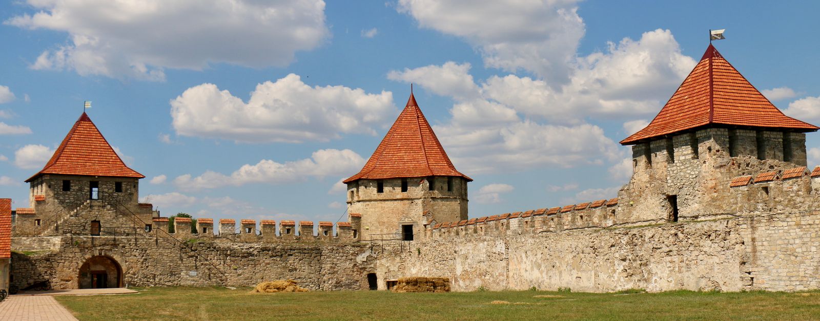 Historic Tighina Fortress in Moldova with stone walls and red turrets under a bright blue sky.