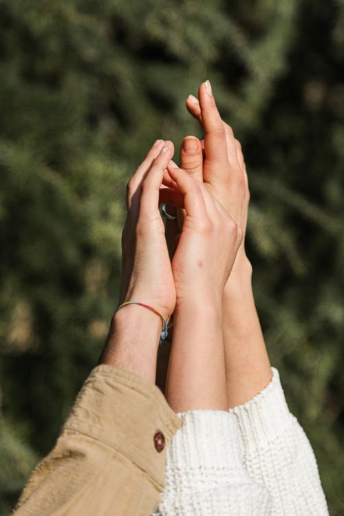 Free Close-up of two pairs of hands touching against a blurred outdoor background symbolizing connection. Stock Photo