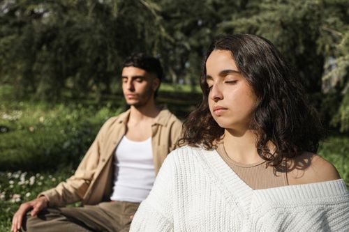 Free Two adults peacefully meditating outdoors under serene nature views. Stock Photo