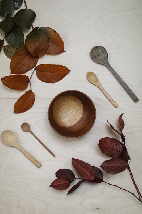 Free A Wooden Bowl and Spoons Near the Leaves Stock Photo