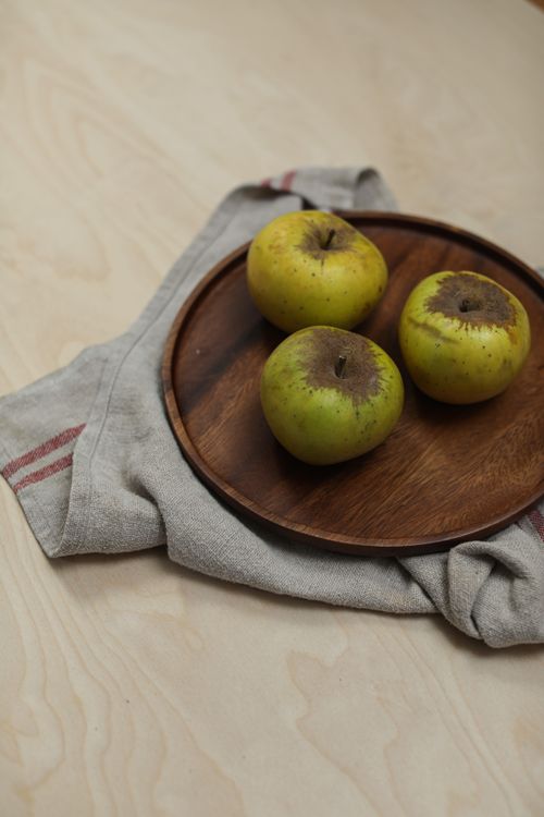 Free Three green apples on a wooden plate, creating a rustic and healthy vibe. Stock Photo