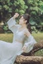 A Woman in White Skirt Sitting on a Tree Trunk