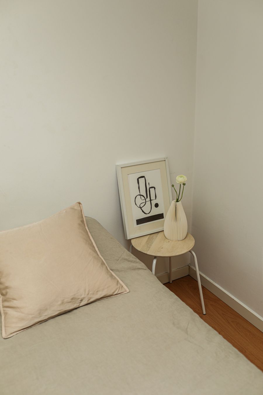 Minimalist bedroom in neutral tones with simple bedding and pale walls