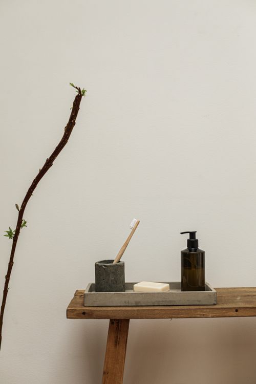 Free A simple arrangement of bathroom items including a wooden toothbrush and liquid soap dispenser. Stock Photo