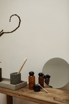A minimalist setup with toothbrush, vials, and mirror on a wooden shelf.