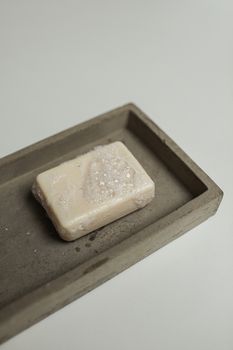 Detailed view of a soap bar resting on a minimalist concrete tray with visible bubbles. - Fotografer Sidoarjo