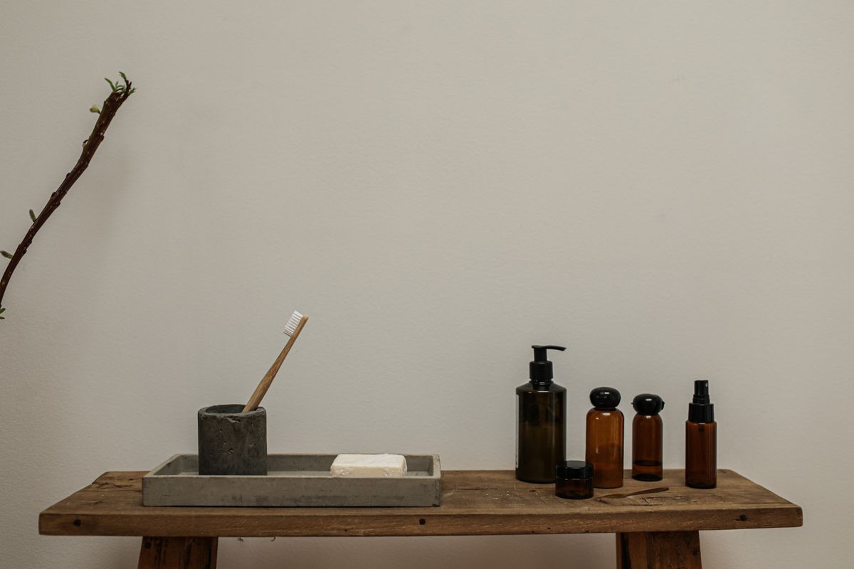 A rustic bathroom setup with soap and amber bottles on a wooden bench for a minimalist look. Stock Photo.