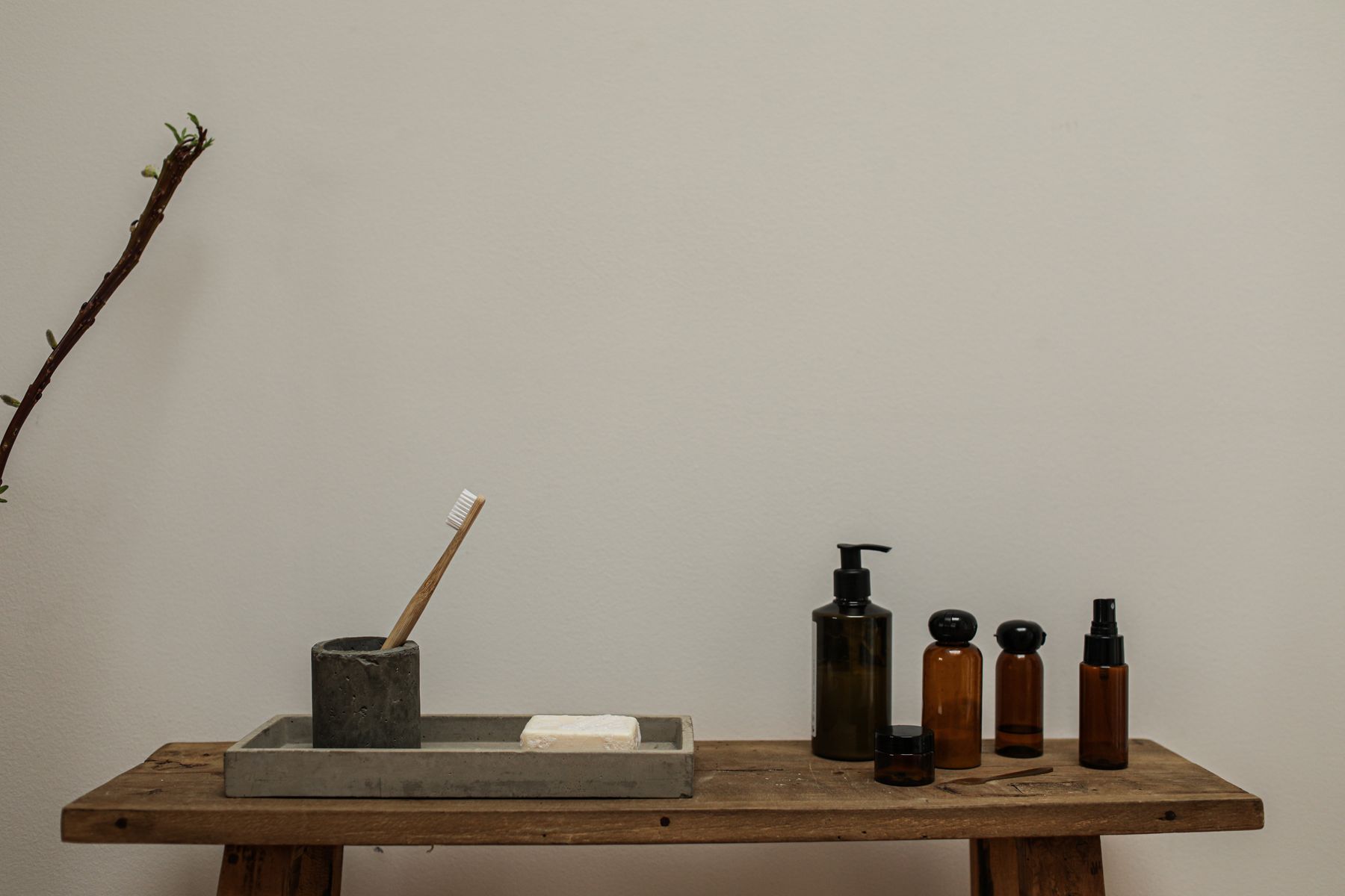 Rustic bathroom detail with amber bottles and natural grooming items on a wooden bench