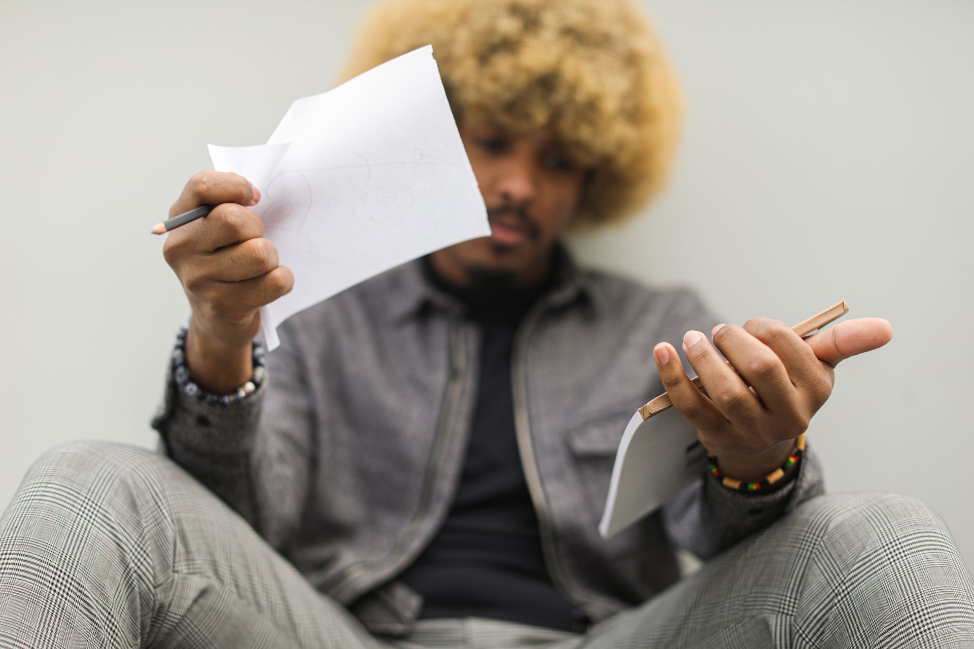 Thoughtful African American man holding a notebook and papers, sitting indoors.