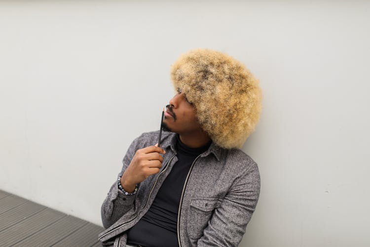 Curly Haired Man Looking Up While Holding A Pencil 