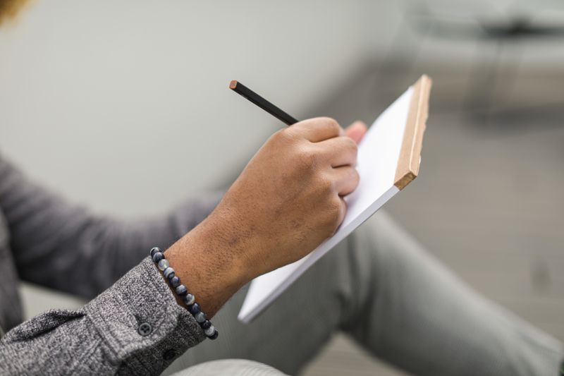 A hand writing in an open notebook on a desk